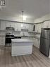 Kitchen featuring stainless steel appliances, decorative backsplash, sink, pendant lighting, and light wood-type flooring - 25 Isherwood Avenue Unit# 42, Cambridge, ON 