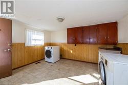 Clothes washing area with wood walls, cabinets, and washing machine and dryer - 