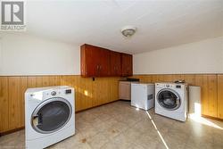 Laundry area featuring wood walls, cabinets, and independent washer and dryer - 