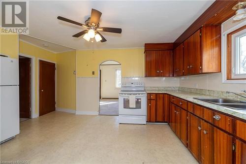 Kitchen featuring decorative backsplash, sink, white appliances, and ceiling fan - 1710 7Th Avenue E, Owen Sound, ON - Indoor Photo Showing Kitchen With Double Sink