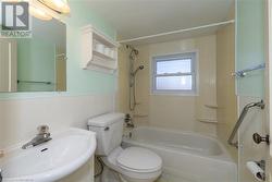 Full bathroom with sink, tiled shower / bath combo, tile walls, and toilet - 