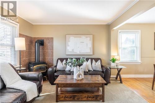 Living room featuring a wealth of natural light, crown molding, light hardwood / wood-style flooring, and a wood stove - 645 Weber Street E, Kitchener, ON - Indoor Photo Showing Living Room