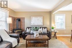 Living room featuring a wealth of natural light, crown molding, light hardwood / wood-style flooring, and a wood stove - 