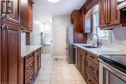 Kitchen featuring tasteful backsplash, sink, light tile patterned floors, and stainless steel appliances - 