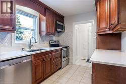 Kitchen with tasteful backsplash, appliances with stainless steel finishes, sink, and light tile patterned floors - 