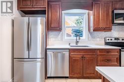 Kitchen featuring stainless steel appliances, light tile patterned flooring, sink, and tasteful backsplash - 