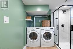 Laundry area with light wood-type flooring and washing machine and dryer - 