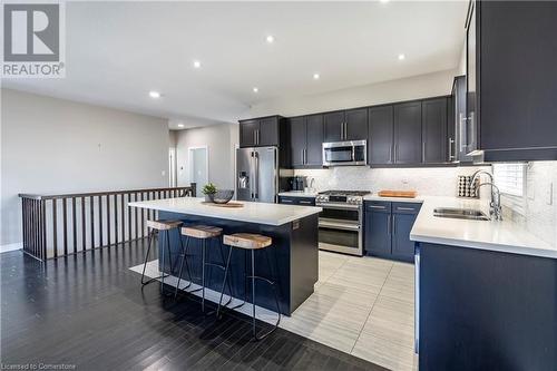 Kitchen featuring light hardwood / wood-style floors, sink, appliances with stainless steel finishes, a kitchen bar, and a kitchen island - 219 Falconridge Drive, Waterloo, ON - Indoor Photo Showing Kitchen With Stainless Steel Kitchen With Double Sink With Upgraded Kitchen