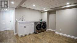 Laundry room with cabinets, separate washer and dryer, sink, and light hardwood / wood-style flooring - 