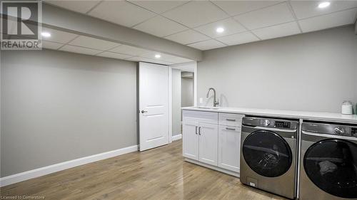 Clothes washing area with cabinets, light hardwood / wood-style flooring, sink, and washing machine and clothes dryer - 219 Falconridge Drive, Waterloo, ON - Indoor Photo Showing Laundry Room