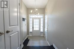 Doorway to outside featuring an inviting chandelier and tile patterned flooring - 