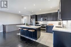 Kitchen featuring light hardwood / wood-style floors, sink, appliances with stainless steel finishes, a kitchen bar, and a kitchen island - 