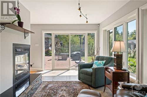 Large sun room with plenty of natural light and 3-way remote controlled gas fireplace and porcelain tile flooring. - 10 Riverbrook Road, Ottawa, ON - Indoor Photo Showing Living Room