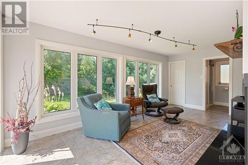 Large sun room with plenty of natural light and 3-way remote controlled gas fireplace and porcelain tile flooring. - 10 Riverbrook Road, Ottawa, ON - Indoor Photo Showing Living Room