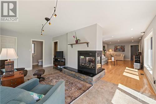 Large sun room with plenty of natural light and 3-way remote controlled gas fireplace and porcelain tile flooring. - 10 Riverbrook Road, Ottawa, ON - Indoor Photo Showing Living Room With Fireplace