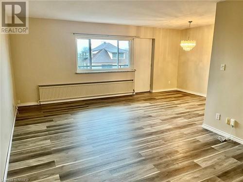 Spare room featuring a chandelier, radiator heating unit, and wood-type flooring - 810 Main Street W Unit# 302, North Bay, ON - Indoor Photo Showing Other Room