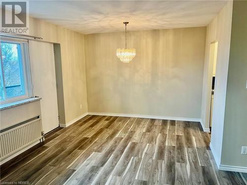 Empty room with dark hardwood / wood-style flooring and an inviting chandelier - 810 Main Street W Unit# 302, North Bay, ON - Indoor Photo Showing Other Room