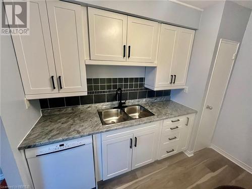 Kitchen featuring decorative backsplash, white dishwasher, sink, light hardwood / wood-style flooring, and white cabinetry - 810 Main Street W Unit# 302, North Bay, ON - Indoor Photo Showing Kitchen With Double Sink