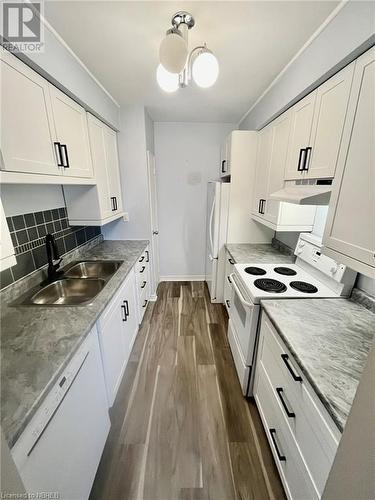 Kitchen featuring white cabinets, white appliances, sink, and dark hardwood / wood-style floors - 810 Main Street W Unit# 302, North Bay, ON - Indoor Photo Showing Kitchen With Double Sink