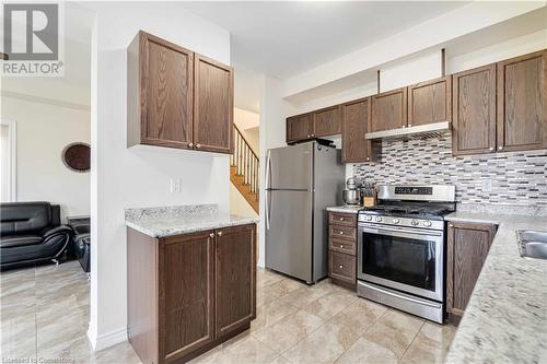 Kitchen featuring backsplash, sink, light tile patterned floors, appliances with stainless steel finishes, and light stone counters - 40 Todd Crescent, Dundalk, ON - Indoor Photo Showing Kitchen With Stainless Steel Kitchen