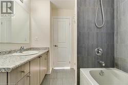 Bathroom with tile patterned flooring, tiled shower / bath combo, and vanity - 