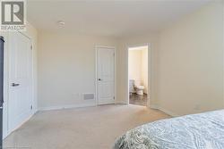 Bedroom with light carpet and ensuite bathroom - 