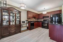 Kitchen with sink, black appliances, tasteful backsplash, decorative light fixtures, and light wood-type flooring - 