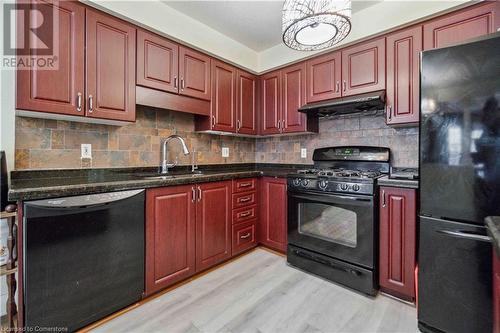 Kitchen featuring dark stone counters, black appliances, sink, extractor fan, and light wood-type flooring - 42 Donnenwerth Drive, Kitchener, ON - Indoor Photo Showing Kitchen With Double Sink