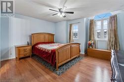 Bedroom with ceiling fan, multiple windows, and light wood-type flooring - 