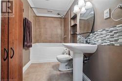 Bathroom with tile patterned floors, toilet, crown molding, and tasteful backsplash - 