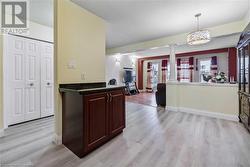 Kitchen with dark brown cabinetry, kitchen peninsula, pendant lighting, decorative columns, and light wood-type flooring - 