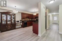 Kitchen with black appliances, hanging light fixtures, decorative backsplash, and light hardwood / wood-style floors - 