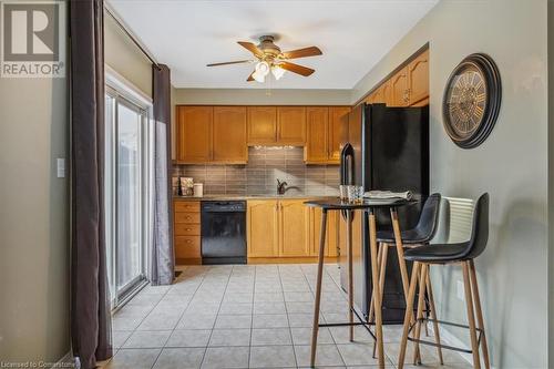 Kitchen with sink, black dishwasher, a breakfast bar area, decorative backsplash, and light tile patterned floors - 24 Kenyon Crescent Unit# 45, Grimsby, ON - Indoor