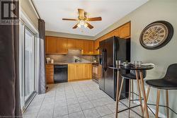 Kitchen featuring decorative backsplash, ceiling fan, sink, black appliances, and light tile patterned floors - 