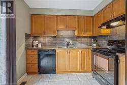 Kitchen with stone counters, light tile patterned floors, backsplash, and black appliances - 