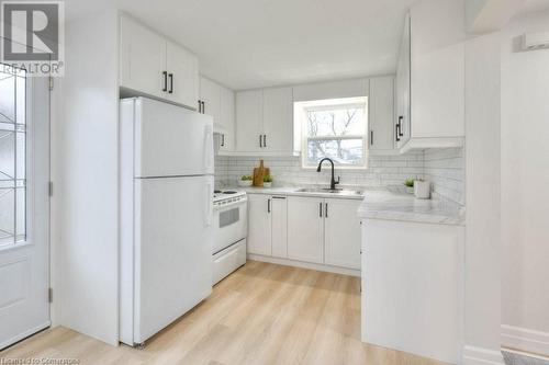 Kitchen with white cabinets, white appliances, light wood-style floors, and sink - 24 Karen Walk, Waterloo, ON - Indoor Photo Showing Kitchen