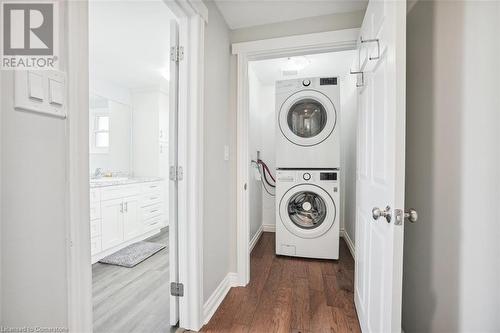 Laundry area with stacked washer / drying machine, sink, and dark wood-type flooring - 25 Rockwood Avenue, St. Catharines, ON - Indoor Photo Showing Laundry Room