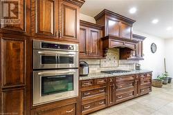 Kitchen featuring light stone countertops, light tile patterned floors, backsplash, and stainless steel appliances - 