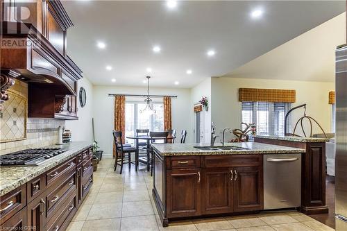 Kitchen featuring light stone countertops, sink, hanging light fixtures, stainless steel gas cooktop, and light tile patterned floors - 59 Dominion Drive, Guelph, ON - Indoor Photo Showing Kitchen With Double Sink With Upgraded Kitchen