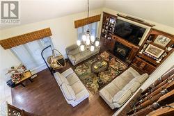 Living room featuring vaulted ceiling, dark wood-type flooring, and an inviting chandelier - 