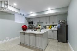 Kitchen featuring sink, gray cabinets, fridge, and a kitchen island with sink - 