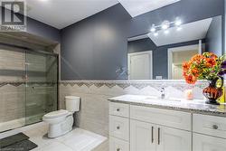 Bathroom with walk in shower, vanity, tile walls, and toilet - 