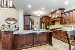 Kitchen with sink, an island with sink, stainless steel appliances, and light tile patterned floors - 