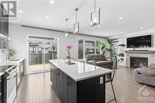 Full quartz island with storage underneath and hanging light fixtures- perfect for hosting & friends (No sink in the island) - 272 Big Dipper Street, Ottawa, ON - Indoor With Fireplace