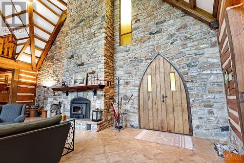 Arched door surrounded by stunning stone wall that includes fireplace with woodstove insert. - 2499 Bathurst Concession 2 Road, Perth, ON - Indoor With Fireplace