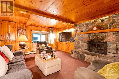 Lower level family room with 2nd Georgian Bay field-stone, wood-burning fireplace - 1102 Ebbs Bay Road, Carleton Place, ON - Indoor Photo Showing Living Room With Fireplace