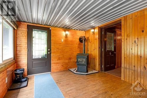 Pellet stove in sunroom - 1102 Ebbs Bay Road, Carleton Place, ON - Indoor Photo Showing Other Room With Fireplace