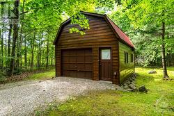 Detached single car garage with woodstove; at back is staircase to upper loft - 