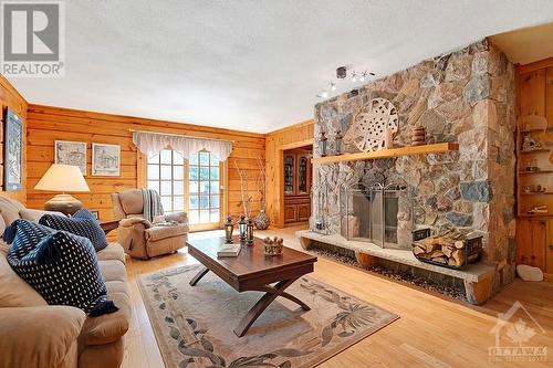 Living room 8' floor ceiling, ash hardwood floor and Georgian Bay field-stone, wood-burning fireplace - 1102 Ebbs Bay Road, Carleton Place, ON - Indoor Photo Showing Living Room With Fireplace