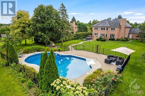 Beautifully landscaped 0.7 acre with heated, salt-water in-ground pool - 5525 Pettapiece Crescent, Manotick, ON - Outdoor With In Ground Pool With Backyard